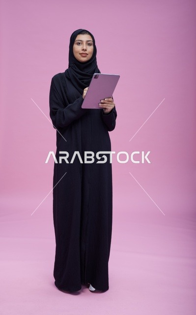 Saudi Woman with Tablet on Pink Studio Background