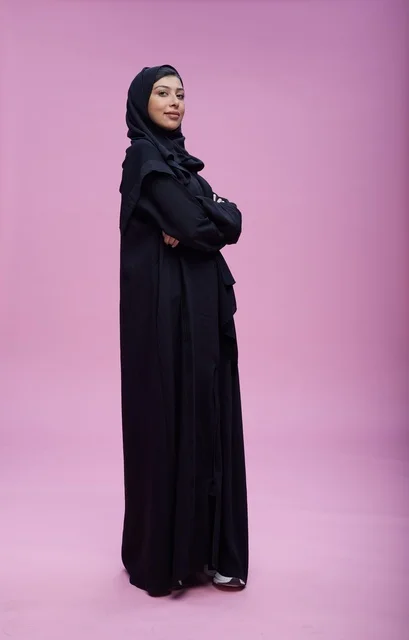 Saudi Woman in Black Abaya on Pink Studio Background