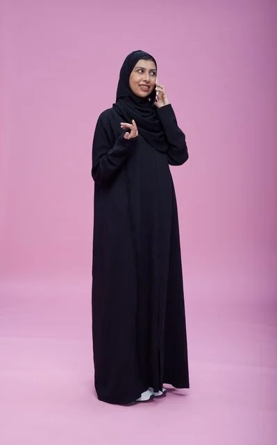 امرأة سعودية بالعباءة تتحدث بالجوال خلفية وردية