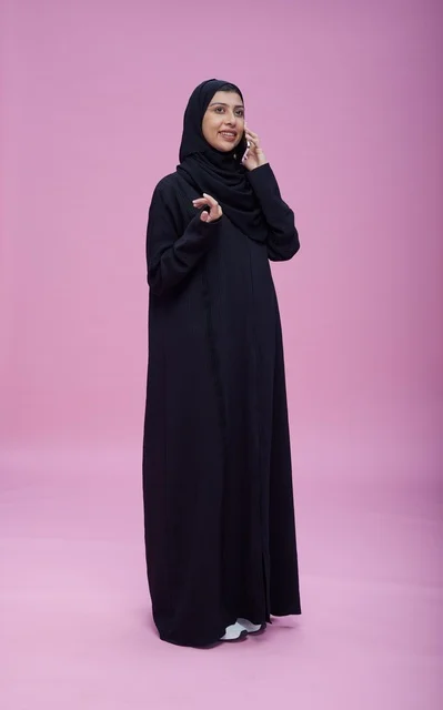 امرأة سعودية بالعباءة السوداء تتحدث عبر الهاتف الذكي