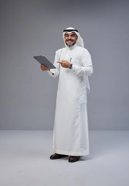 رجل سعودي بالزي التقليدي يستخدم جهازاً لوحياً في الاستوديو