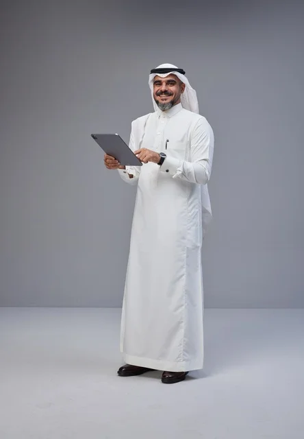 Saudi Man in Traditional Thobe Using Tablet