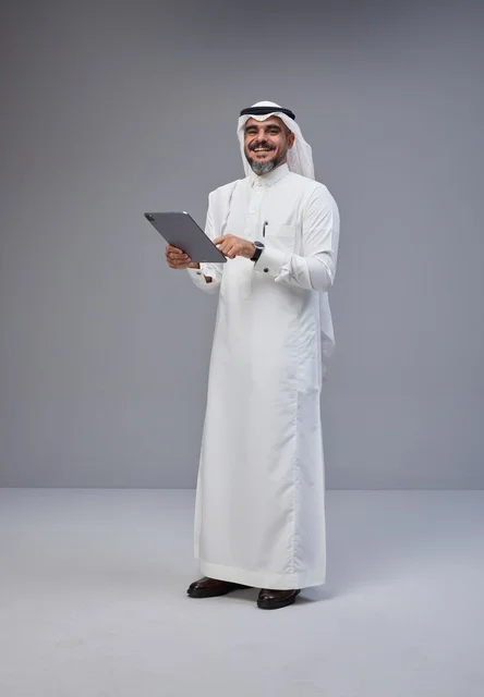 Saudi Man in Traditional Thobe Using Tablet