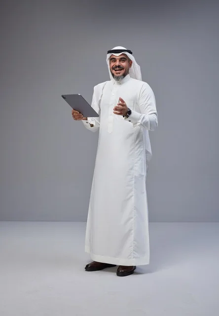 Saudi Man in Traditional Thobe Holding Tablet Studio Shot