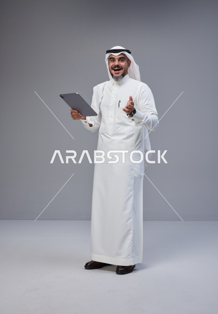 Saudi Man in Traditional Thobe Holding Tablet