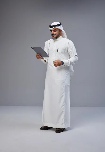 رجل سعودي بالزي التقليدي يستخدم جهازاً لوحياً في استوديو