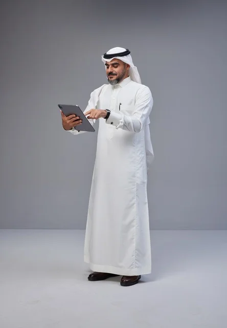 رجل سعودي بالزي التقليدي يستخدم جهاز لوحي
