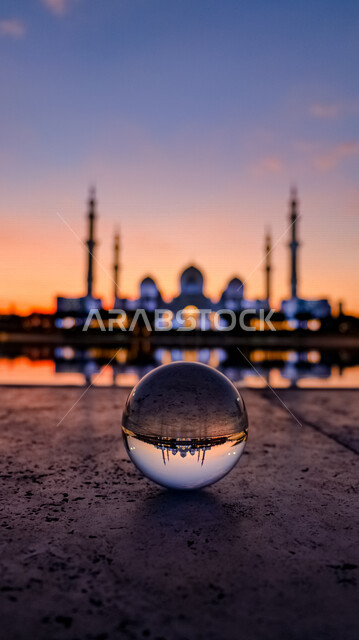كرة زجاجية تعكس جامع الشيخ زايد بن سلطان آل نهيان في أبوظبي بدولة الإمارات العربية المتحدة ، مسجد الشيخ زايد بأبو ظبي ، الفن الاسلامي المعماري في الإمارات ، إنعكاس مسجد الشيخ زايد وقت الغروب عبر البلور ، تركيز تصوير تجميعي على الكرة الزجاجية