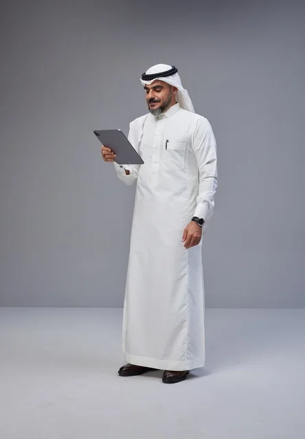 Saudi Man in Traditional Thobe Using Digital Tablet