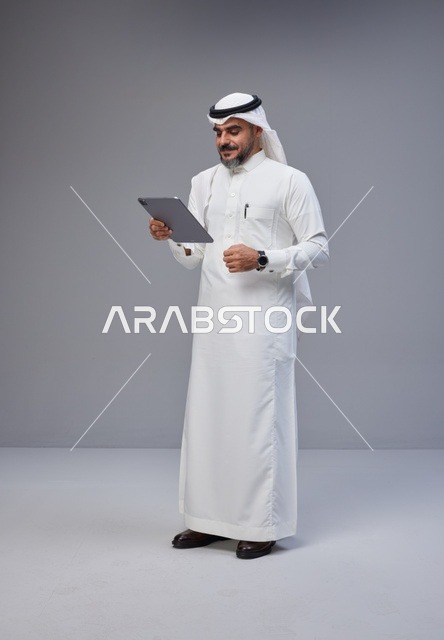 رجل سعودي بالزي التقليدي يستخدم جهاز لوحي