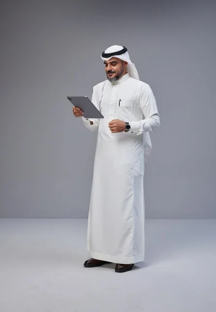 Saudi Man in Traditional Thobe Using Tablet in Studio