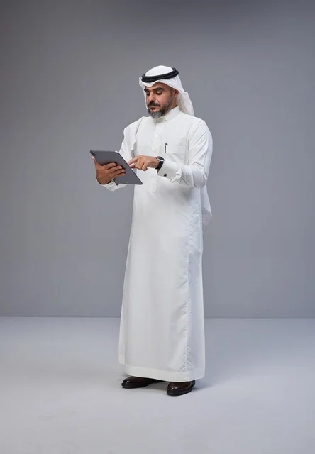 Saudi Man in Traditional Dress Using Tablet in Studio