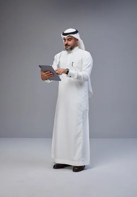 Saudi Man in Traditional Thobe Using Digital Tablet