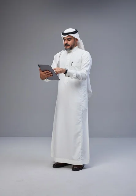 رجل سعودي بالزي التقليدي يستخدم جهاز لوحي
