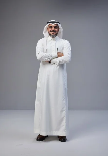 رجل سعودي بالزي التقليدي يقف بثقة مكتف اليدين