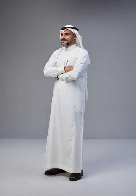 رجل سعودي بالزي التقليدي يقف بوضعية واثقة في الاستوديو