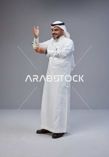 Saudi Man in Traditional Thobe Using Smartphone