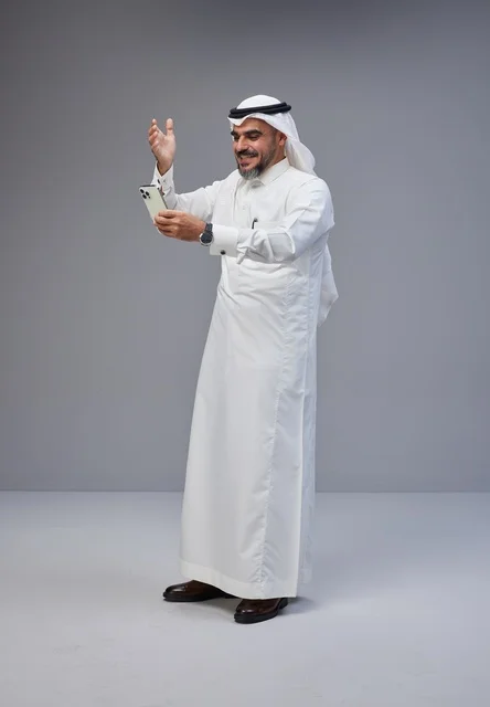 Saudi Man in Traditional Thobe Using Smartphone