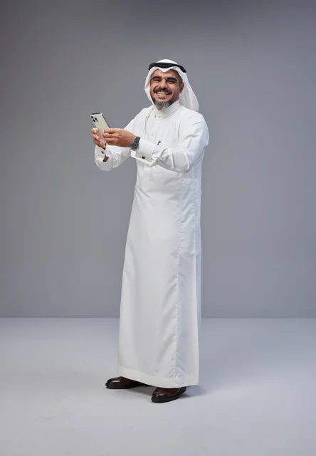 رجل سعودي بالزي التقليدي يستخدم هاتف ذكي