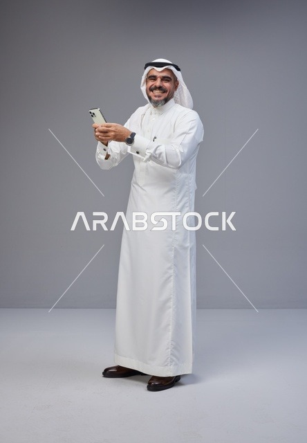 رجل سعودي بالزي التقليدي يستخدم الهاتف الذكي