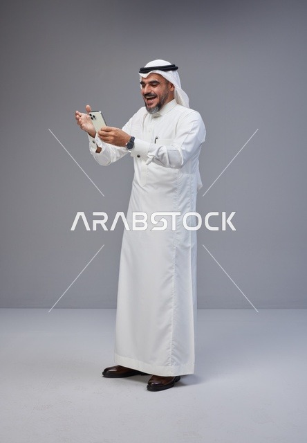 Saudi Man in Traditional Thobe Using Smartphone