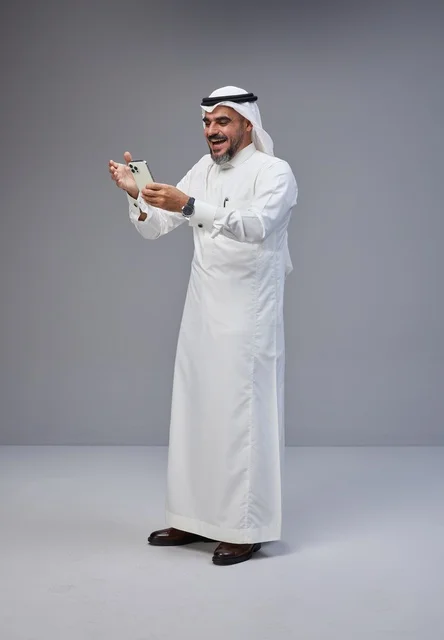 Saudi Man in Traditional Thobe Using Smartphone