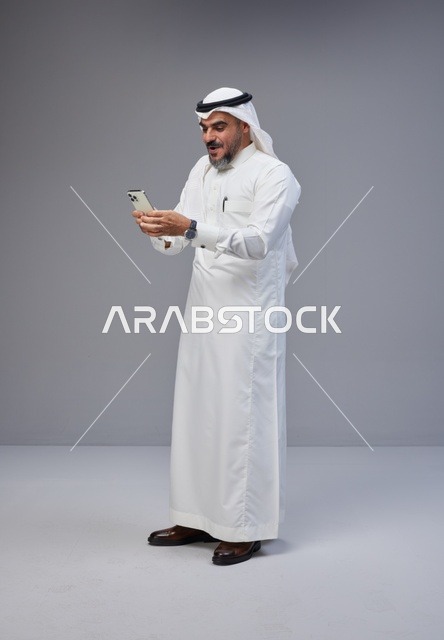 Saudi Man in Traditional Thobe Using Smartphone