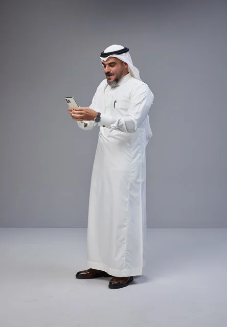 Saudi Man in Traditional Thobe Using Smartphone