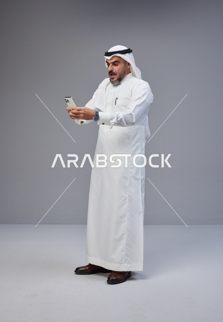 Shocked Saudi Man Using Smartphone in Studio Portrait