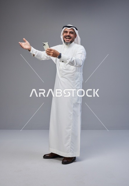 رجل سعودي بالزي التقليدي يستخدم الهاتف الذكي