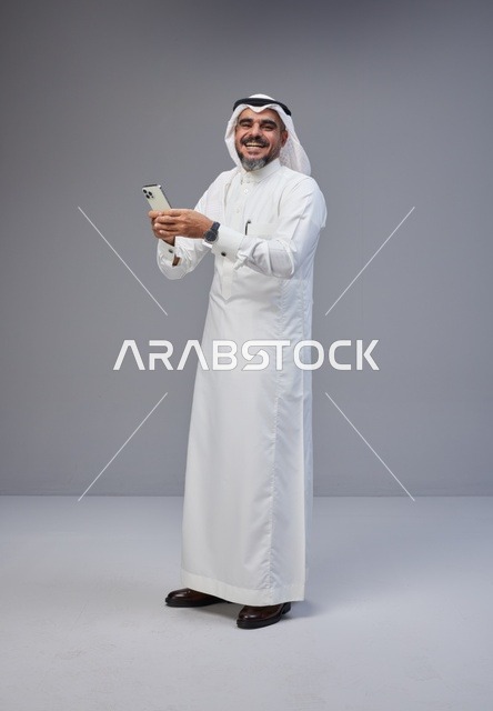 رجل سعودي بالزي التقليدي يستخدم الهاتف الذكي