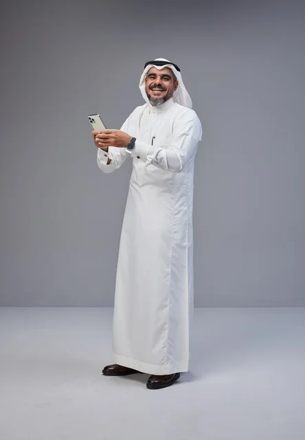 Saudi Man in Traditional Thobe Using Smartphone