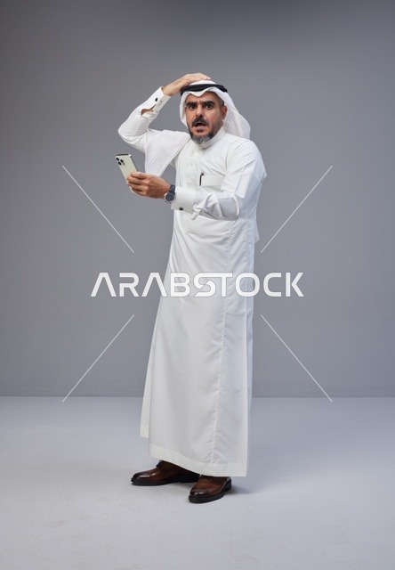 Shocked Saudi Man Looking at Smartphone on Grey Background