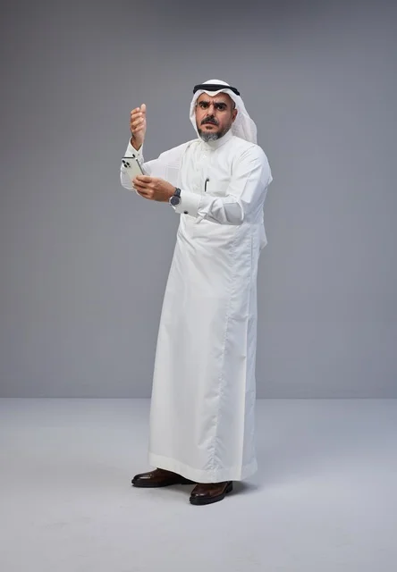 رجل سعودي بالزي التقليدي يستخدم الهاتف الذكي