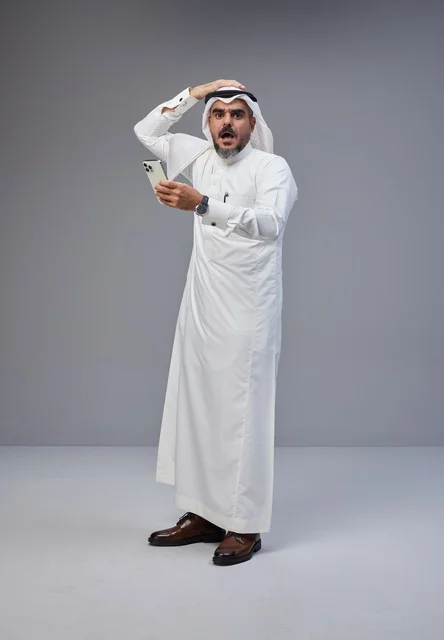 Shocked Saudi Man Using Smartphone on Grey Background