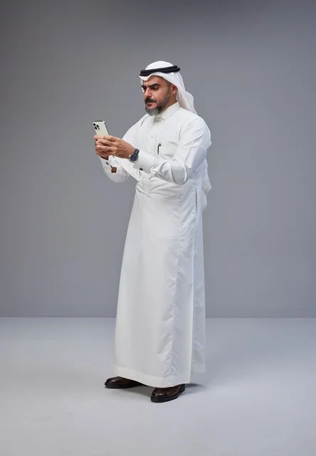 Saudi Man in Traditional Dress Using Smartphone
