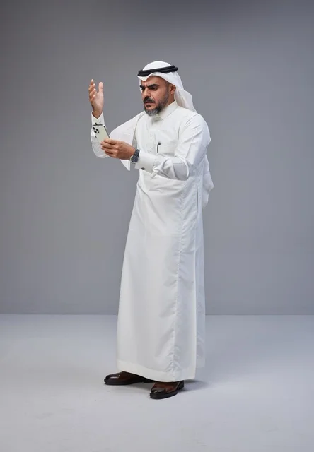 Saudi Man in Traditional Attire Using Smartphone