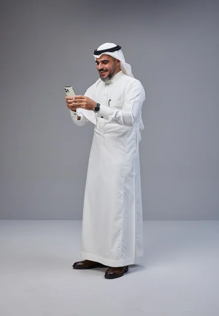 Saudi Man in Traditional Thobe Using Smartphone