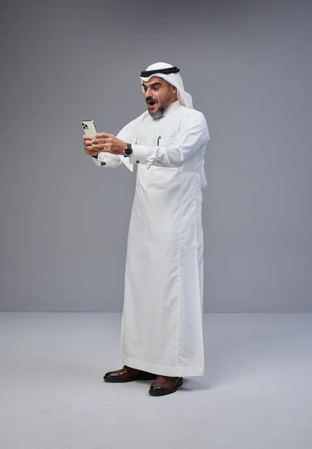 Saudi Man in Traditional Thobe Using Smartphone