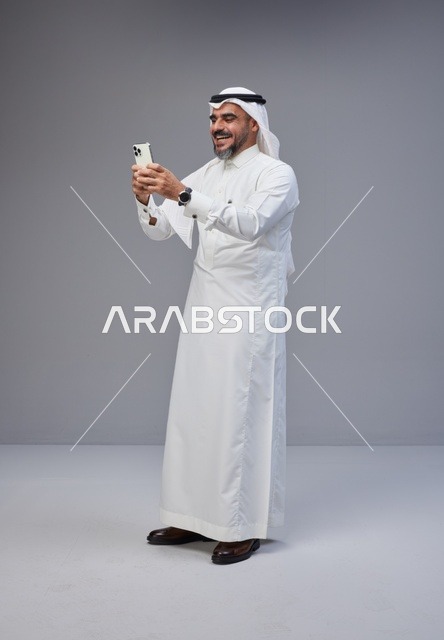 Saudi Man in Traditional Thobe Using Smartphone