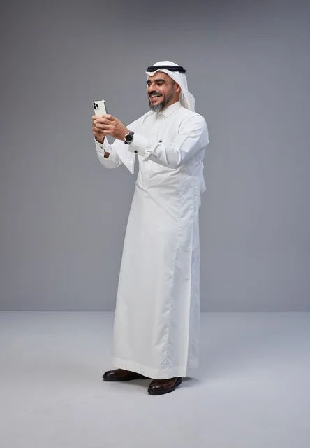 Saudi Man in Traditional Thobe Using Smartphone