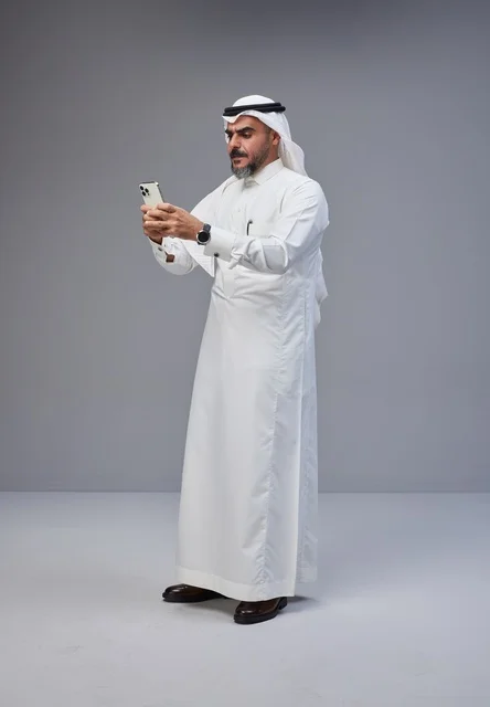 رجل سعودي بالزي التقليدي يستخدم الهاتف الذكي