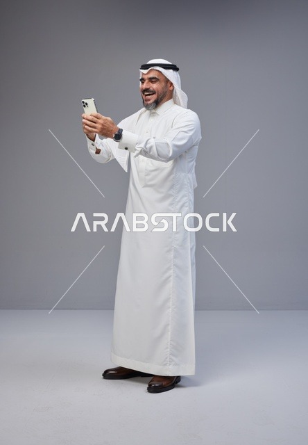 رجل سعودي بالزي التقليدي يستخدم الهاتف الذكي