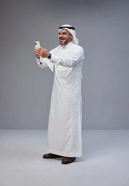 Saudi Man in Traditional Thobe Using Smartphone