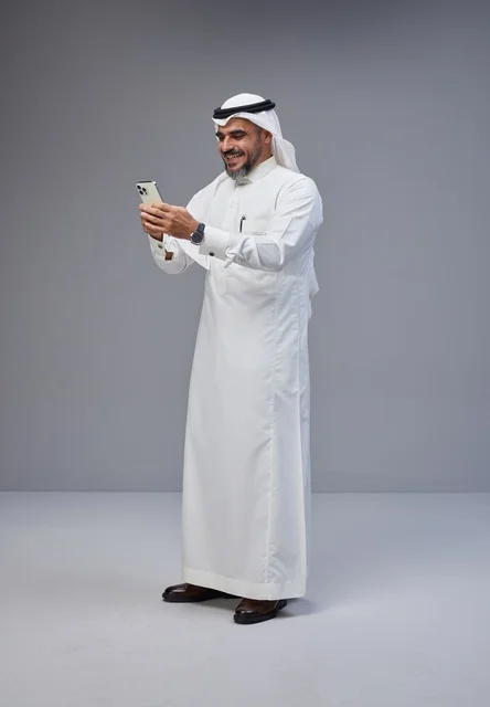 رجل سعودي بالزي التقليدي يستخدم الهاتف الذكي