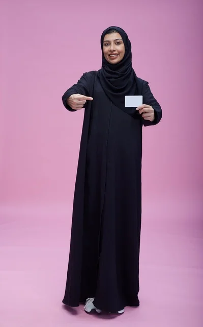 امرأة سعودية تحمل بطاقة بيضاء فارغة بخلفية وردية