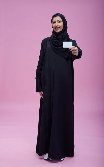 امرأة سعودية بالعباءة تحمل بطاقة فارغة خلفية وردية