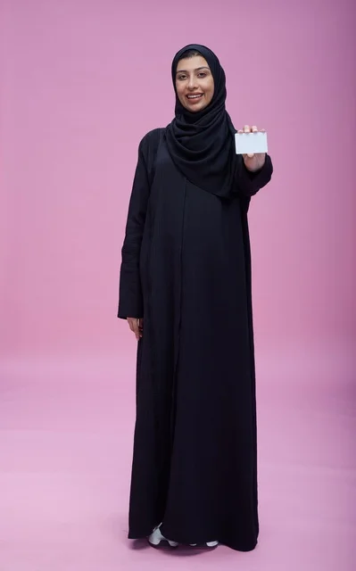 امرأة سعودية تحمل بطاقة بيضاء فارغة بخلفية وردية