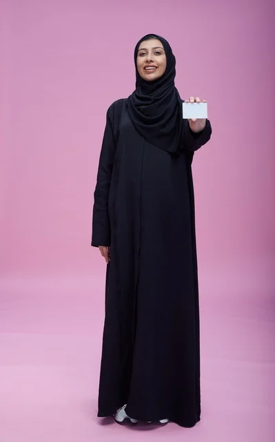 امرأة سعودية بالعباءة تحمل بطاقة عمل فارغة خلفية وردية