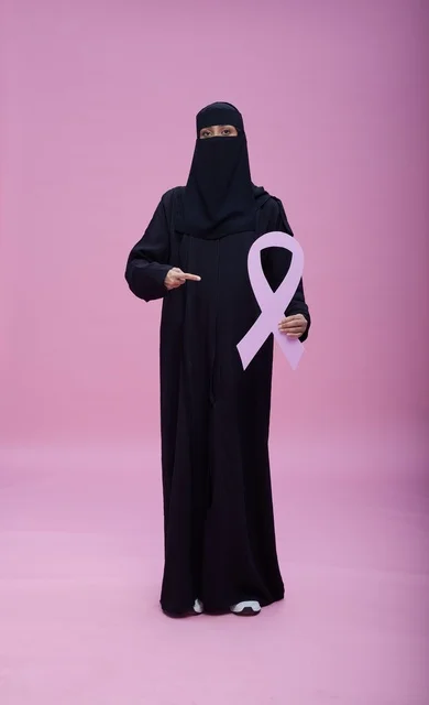 امرأة سعودية بالنقاب تحمل شعار التوعية بسرطان الثدي